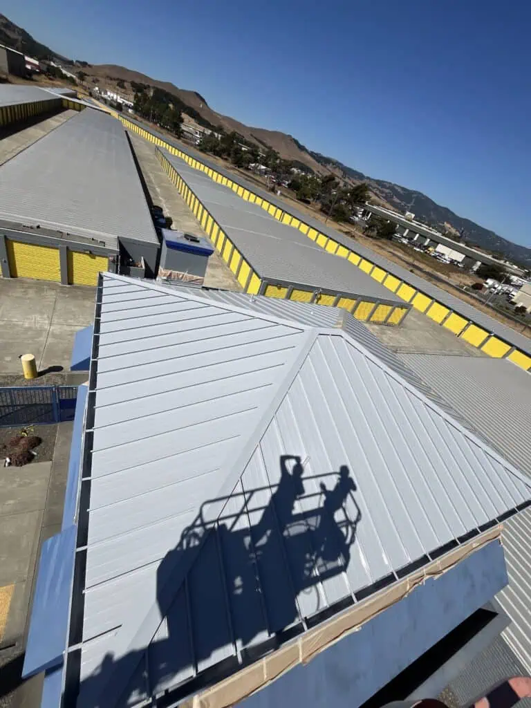 Commercial metal roof painted with protective coating in an industrial area.
